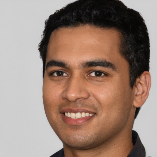 Joyful latino young-adult male with short  black hair and brown eyes