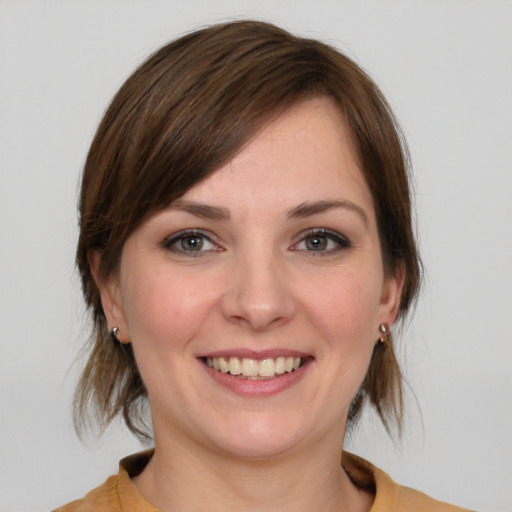 Joyful white young-adult female with medium  brown hair and grey eyes