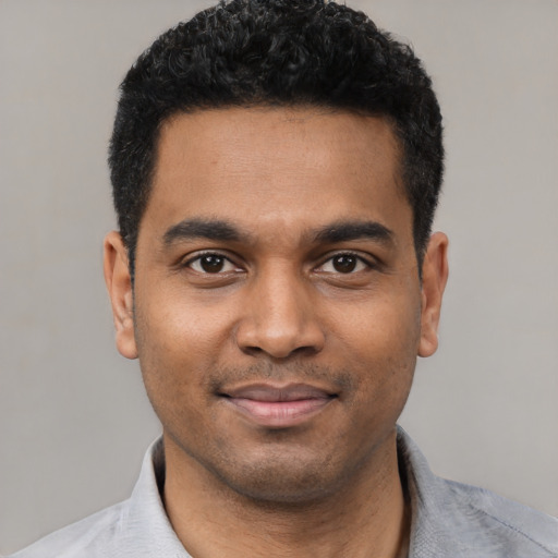 Joyful black young-adult male with short  black hair and brown eyes