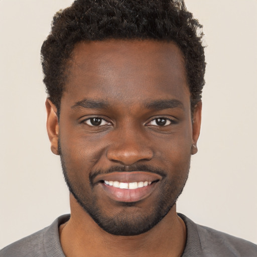 Joyful black young-adult male with short  brown hair and brown eyes