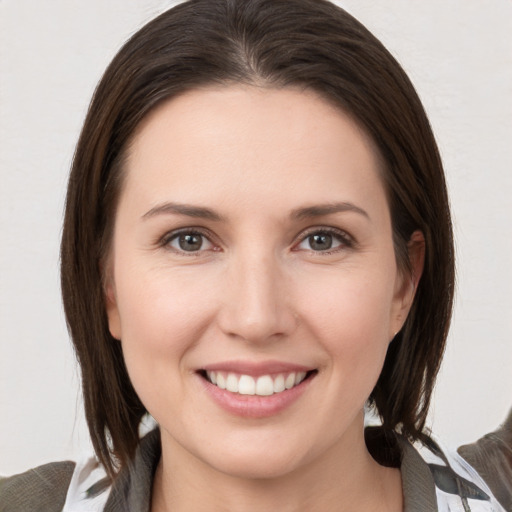 Joyful white young-adult female with medium  brown hair and grey eyes