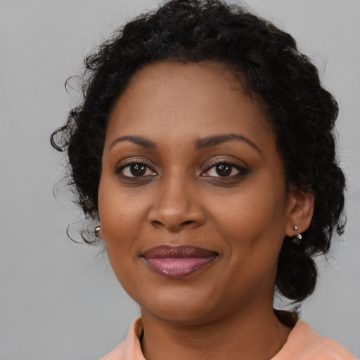 Joyful black adult female with long  brown hair and brown eyes