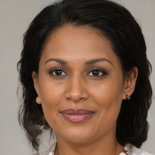 Joyful latino adult female with medium  brown hair and brown eyes