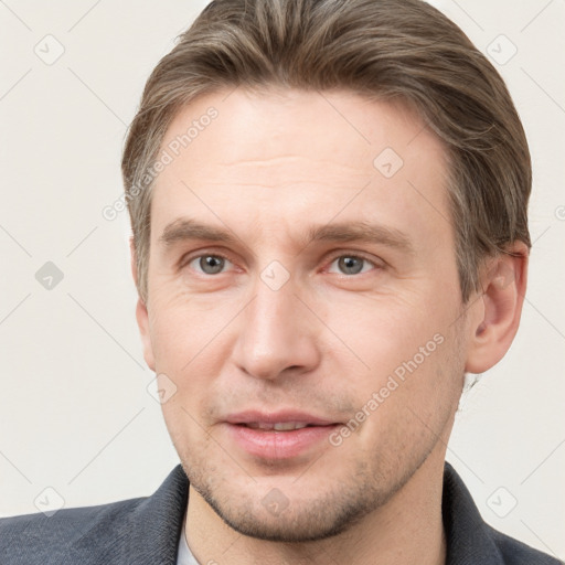 Joyful white young-adult male with short  brown hair and grey eyes