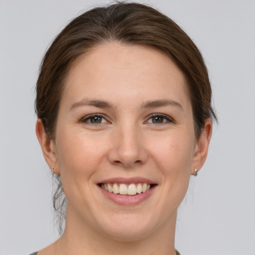 Joyful white young-adult female with medium  brown hair and grey eyes