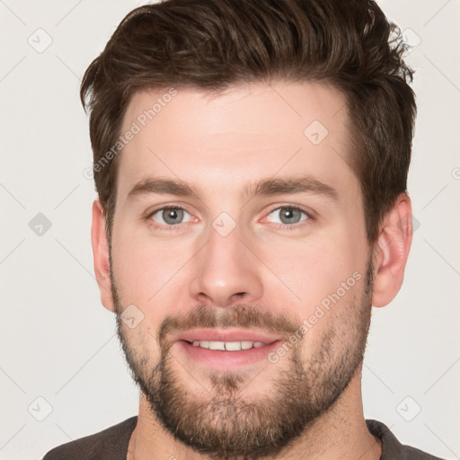 Joyful white young-adult male with short  brown hair and grey eyes