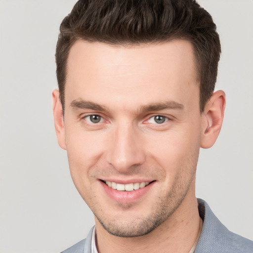 Joyful white young-adult male with short  brown hair and grey eyes