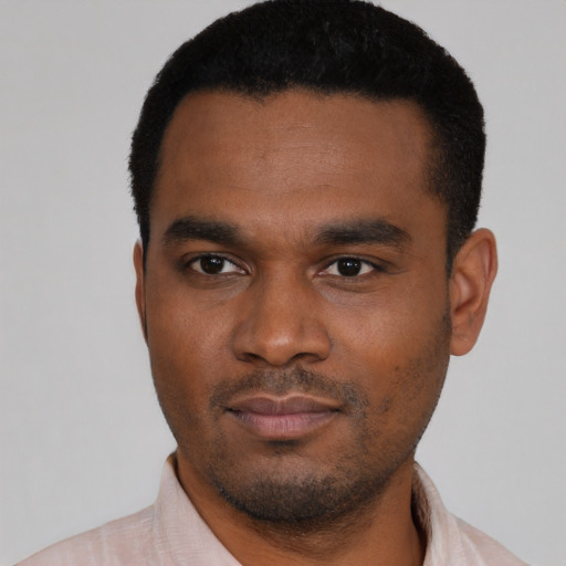 Joyful black young-adult male with short  black hair and brown eyes