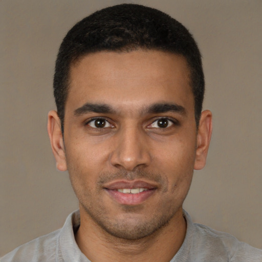 Joyful black young-adult male with short  brown hair and brown eyes