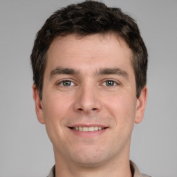 Joyful white young-adult male with short  brown hair and grey eyes