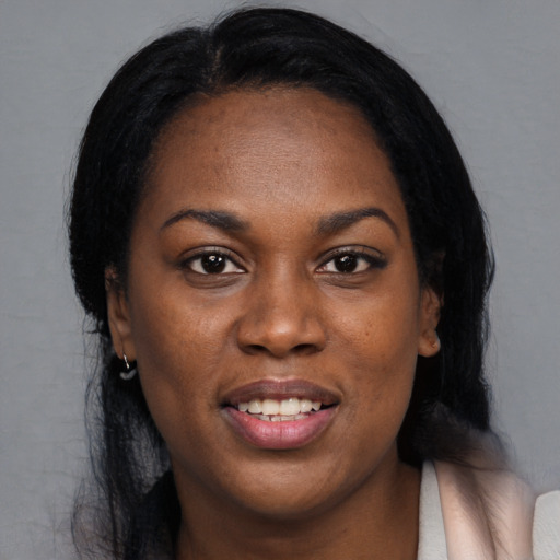 Joyful black young-adult female with long  black hair and brown eyes