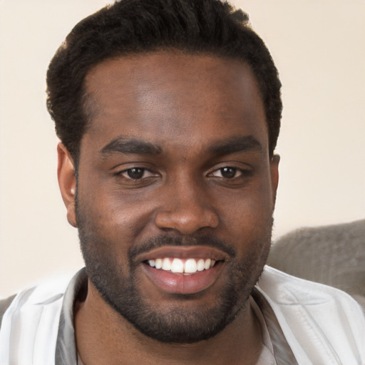 Joyful black young-adult male with short  brown hair and brown eyes