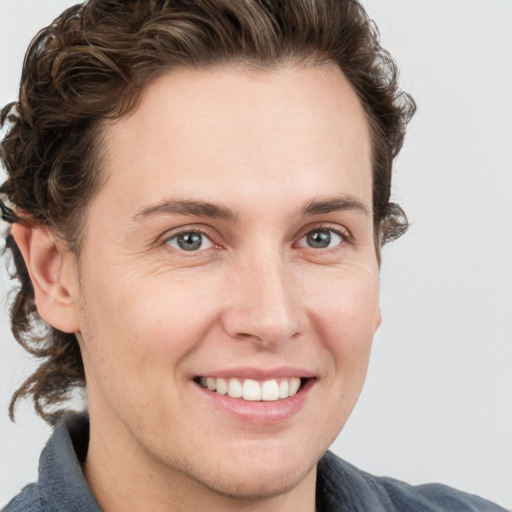 Joyful white young-adult male with medium  brown hair and grey eyes