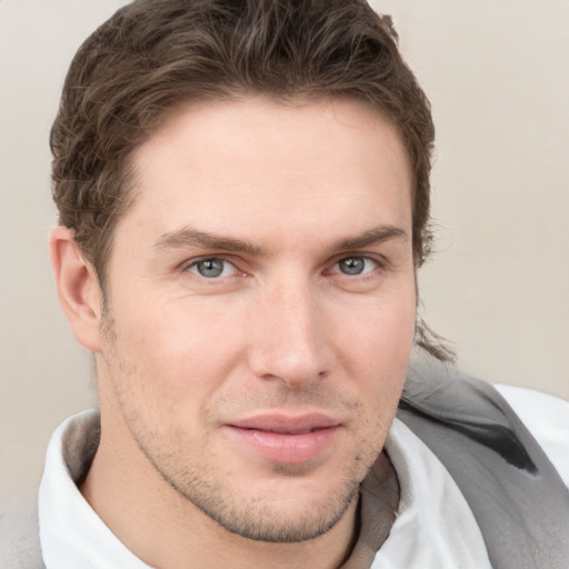 Joyful white young-adult male with short  brown hair and grey eyes