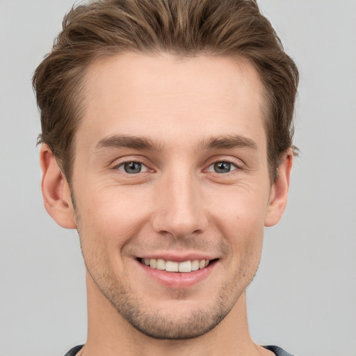 Joyful white young-adult male with short  brown hair and grey eyes