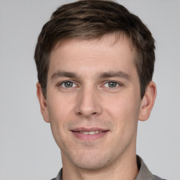 Joyful white young-adult male with short  brown hair and grey eyes