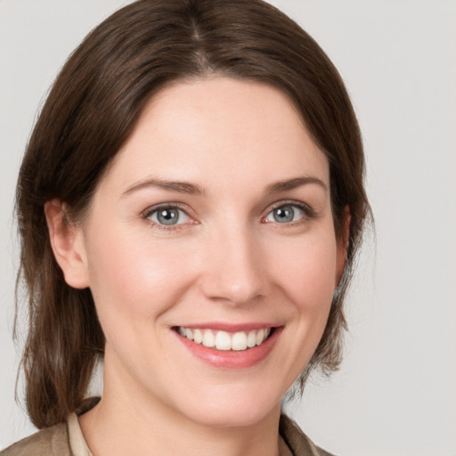 Joyful white young-adult female with medium  brown hair and grey eyes