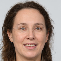 Joyful white adult female with long  brown hair and grey eyes