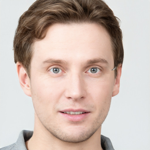 Joyful white young-adult male with short  brown hair and grey eyes