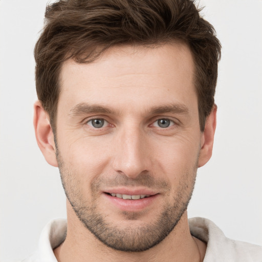 Joyful white young-adult male with short  brown hair and grey eyes