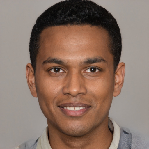 Joyful black young-adult male with short  black hair and brown eyes