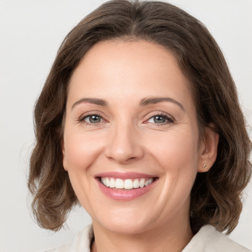 Joyful white young-adult female with medium  brown hair and grey eyes