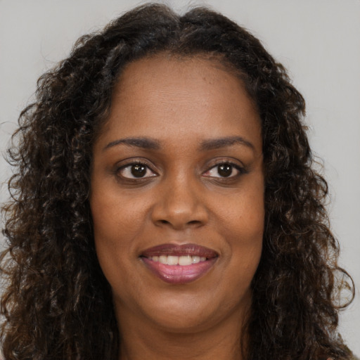 Joyful black young-adult female with long  brown hair and brown eyes