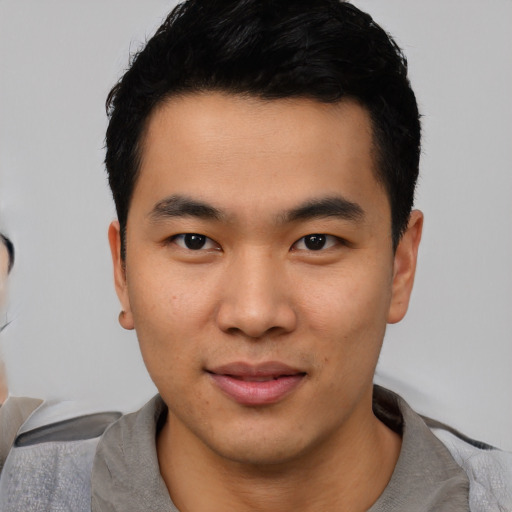 Joyful asian young-adult male with short  black hair and brown eyes