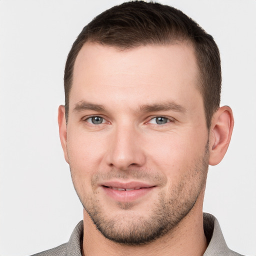 Joyful white young-adult male with short  brown hair and grey eyes