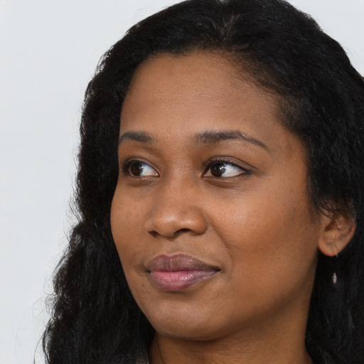 Joyful black young-adult female with long  black hair and brown eyes