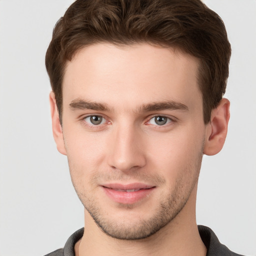 Joyful white young-adult male with short  brown hair and grey eyes