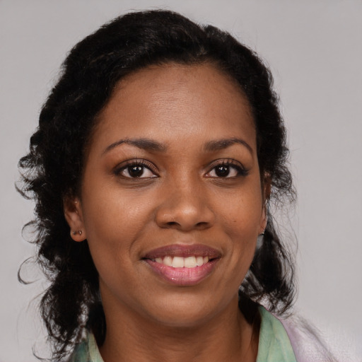 Joyful black young-adult female with long  brown hair and brown eyes