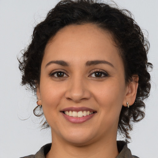 Joyful latino young-adult female with medium  brown hair and brown eyes