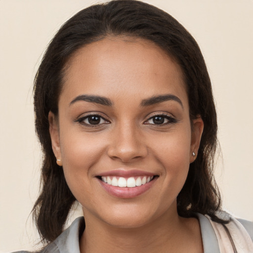 Joyful latino young-adult female with long  brown hair and brown eyes