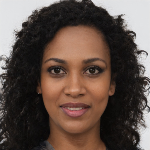 Joyful black young-adult female with long  black hair and brown eyes