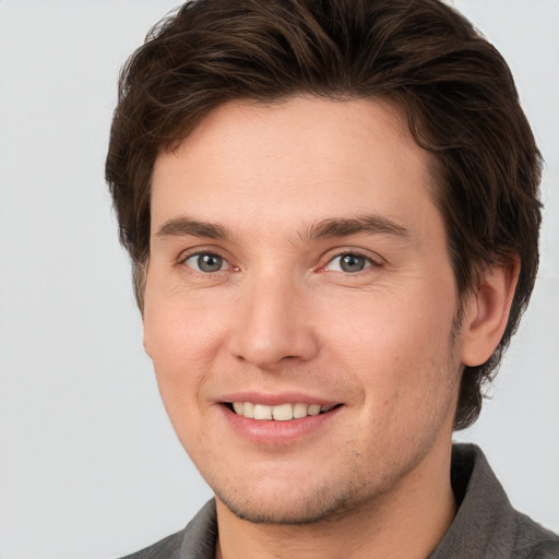 Joyful white young-adult male with short  brown hair and grey eyes