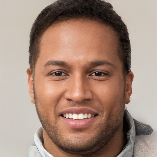 Joyful black young-adult male with short  brown hair and brown eyes