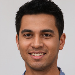 Joyful latino young-adult male with short  black hair and brown eyes