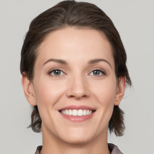 Joyful white young-adult female with medium  brown hair and grey eyes