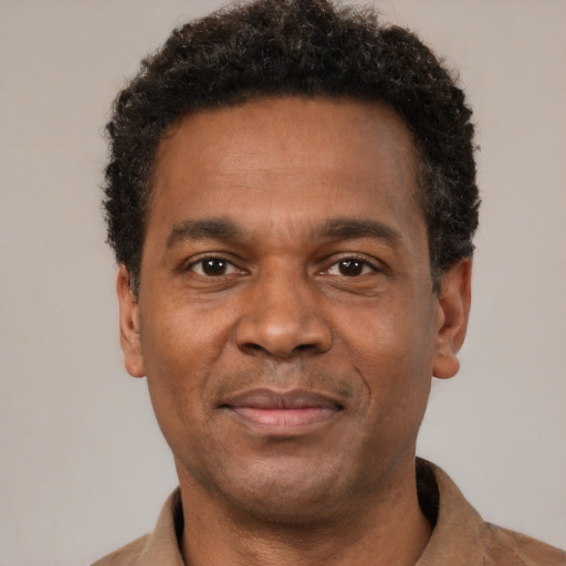 Joyful black adult male with short  black hair and brown eyes