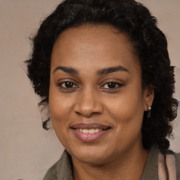 Joyful black young-adult female with long  brown hair and brown eyes