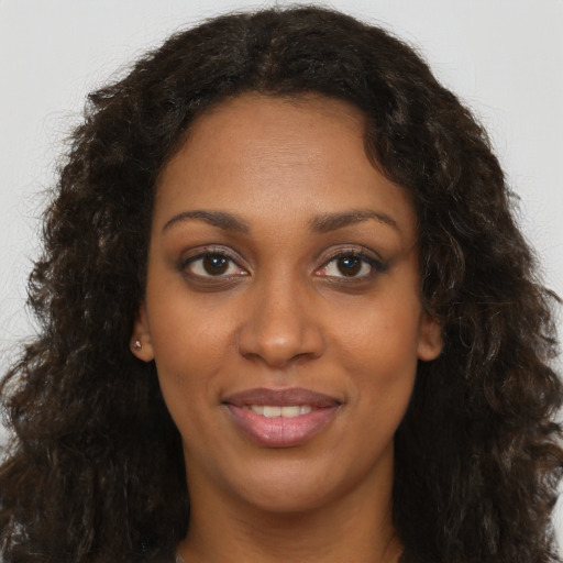 Joyful black young-adult female with long  brown hair and brown eyes