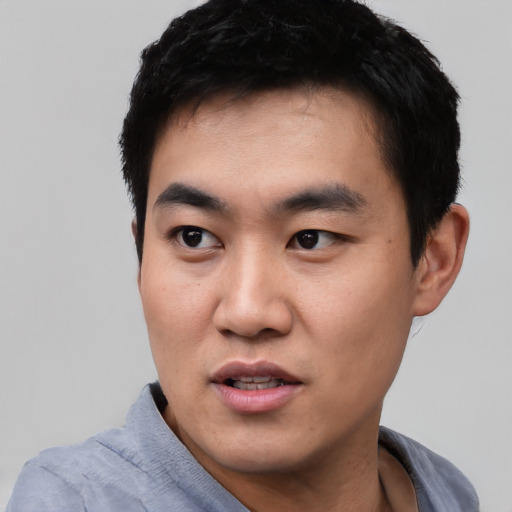 Joyful asian young-adult male with short  black hair and brown eyes