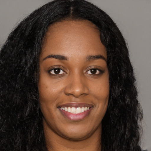 Joyful black young-adult female with long  black hair and brown eyes