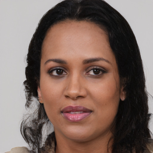 Joyful black young-adult female with long  black hair and brown eyes