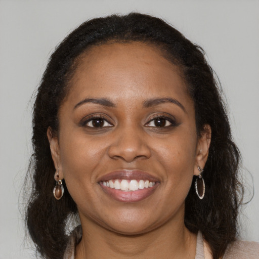 Joyful black young-adult female with long  brown hair and brown eyes