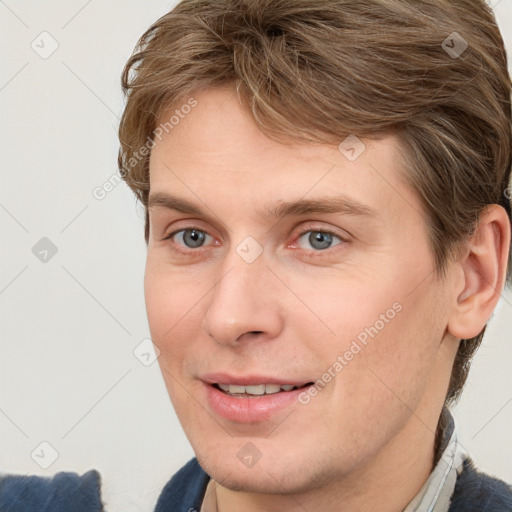 Joyful white young-adult male with short  brown hair and grey eyes