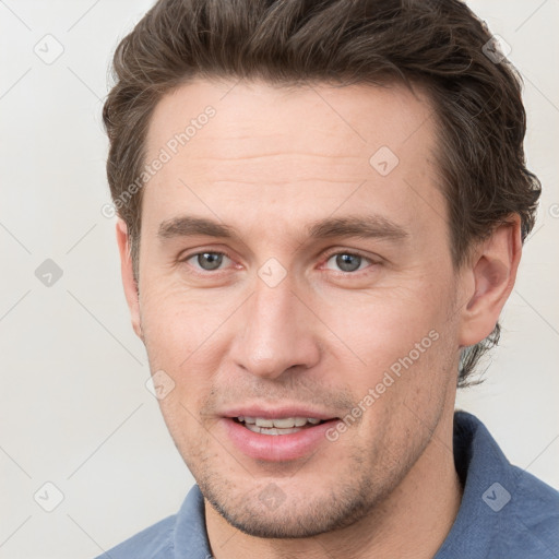 Joyful white young-adult male with short  brown hair and grey eyes