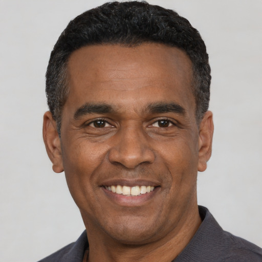 Joyful black adult male with short  black hair and brown eyes