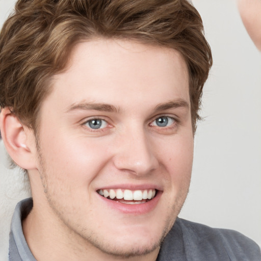 Joyful white young-adult male with short  brown hair and blue eyes